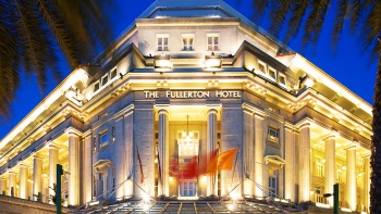 Die Fassade und der Eingang des Fullerton Hotels, flankiert von zwei Palmen