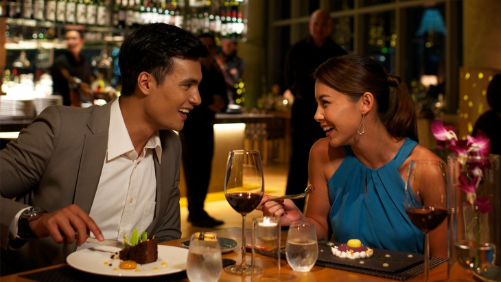 A couple enjoying dessert and wine at restaurant.