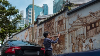 Seorang wanita mengambil foto mural Thian Hock Keng ‏‏‎di Amoy Street 
