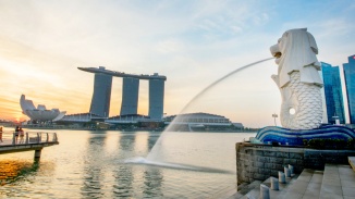 シンガポールのスカイラインを背景に、シンガポール川に向かって水を吐き出すマーライオン像