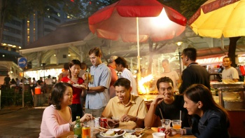 Một nhóm bạn đang ăn các món bình dân bên ngoài Lau Pa Sat