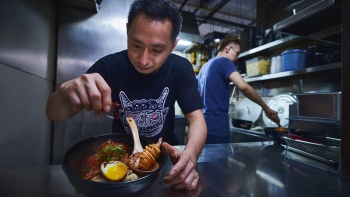 Hình chụp chân dung người chủ A Noodle Story đang trình bày một tô mỳ wanton